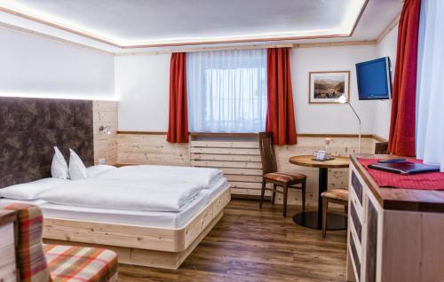 a hotel room with a bed and a desk at Hotel Garni Aghel in Selva di Val Gardena