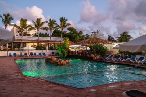 a swimming pool at a resort with chairs and palm trees at Sint Maarten Blue Dream Studio 6 in Cupecoy