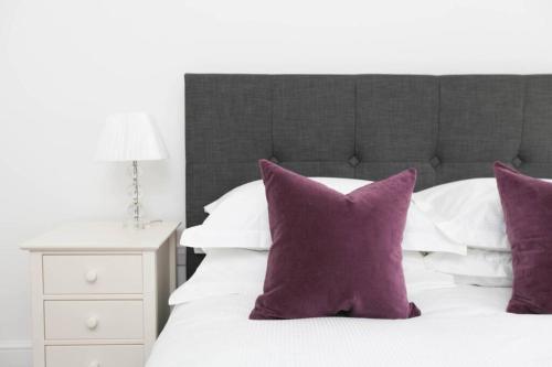 a bedroom with a bed with purple pillows at Raynolds Cottage Blidworth in Blidworth