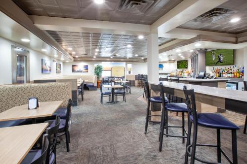 um restaurante com mesas e cadeiras e um bar em Wingate by Wyndham Detroit Metro Airport em Romulus