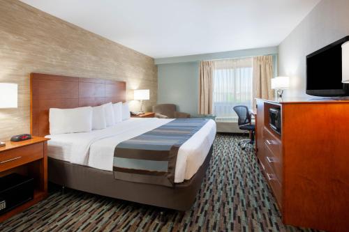 a hotel room with a bed and a flat screen tv at Wingate by Wyndham Detroit Metro Airport in Romulus