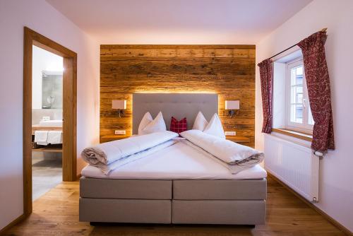 - une chambre avec un grand lit et un mur en bois dans l'établissement Gasthof Herrnhaus, à Brixlegg