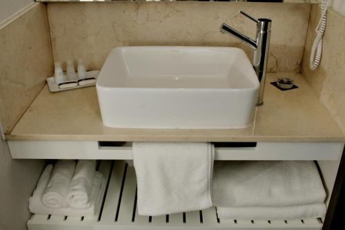 a white sink in a bathroom with towels at Mulen Hotel Tandil in Tandil