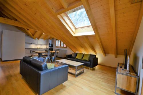 a living room with leather furniture and a skylight at Waterfall View Luxury Penthouse in Lauterbrunnen