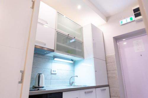a kitchen with white cabinets and a sink at SPA Apartment Nalis in Niš