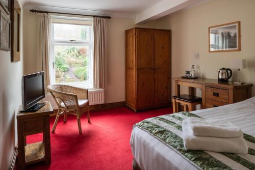 a hotel room with a bed and a desk and a window at Y Talbot in Tregaron