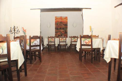 a dining room with tables and chairs with white table cloth at Hotel Casa del Marquez de Bahichala in Barichara