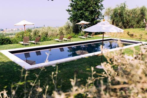 ein Pool mit zwei Sonnenschirmen und zwei Stühlen in der Unterkunft Prati Palai in Bardolino