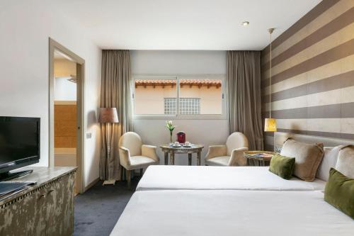 a hotel room with two beds and a television at Globales Acis y Galatea in Madrid