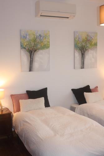 two beds in a bedroom with two paintings on the wall at Casal dos Cantos in Quinta do Anjo