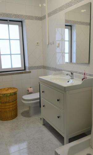 a bathroom with a sink and a toilet and a mirror at Casal dos Cantos in Quinta do Anjo