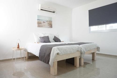 a white bedroom with a large bed and a window at "הפינה שלי בטבריה" in Tiberias