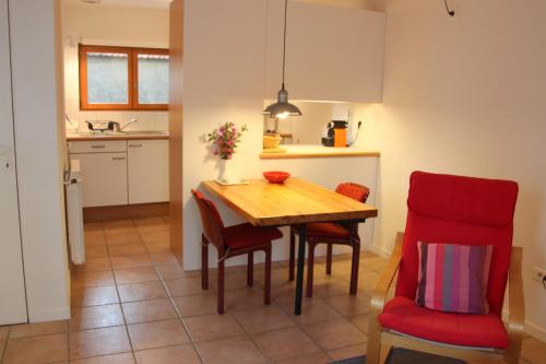 une cuisine et une salle à manger avec une table en bois et des chaises rouges dans l'établissement Paradix holiday apartment - gîte 4, 2 pers, à Nissan-lez-Enserune