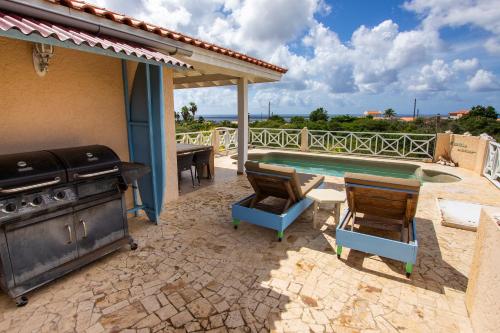 a patio with a grill and chairs next to a pool at Casa di Bon Bientu in Kralendijk