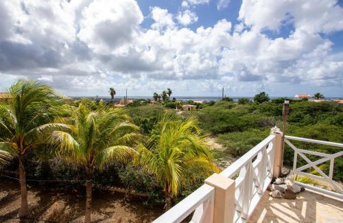 a balcony with palm trees and the ocean in the background at Casa di Bon Bientu in Kralendijk
