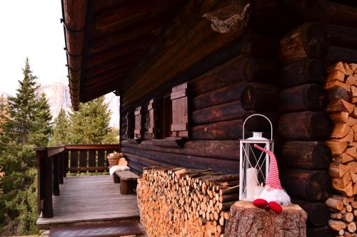 una baita di tronchi con un portico con un cappello di Babbo Natale sopra di Baita Toè a Canazei