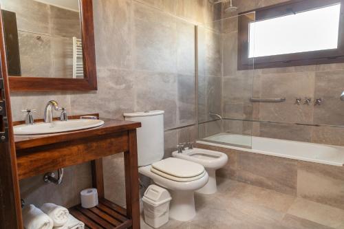 a bathroom with a toilet and a sink and a tub at Hotel Cottbus in San Carlos de Bariloche