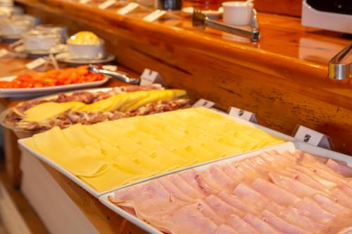 a buffet with meats and cheese and other food at Hotel Cottbus in San Carlos de Bariloche