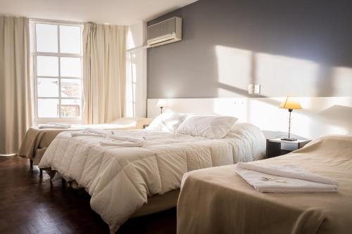 a bedroom with three beds with white sheets and a window at Hotel 376 in Villa Carlos Paz