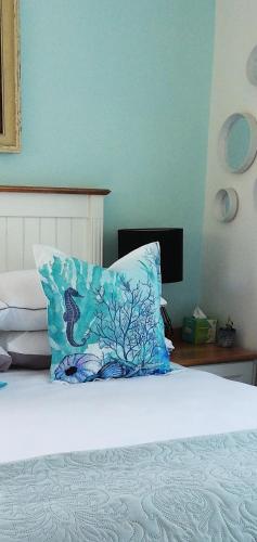 a bed with a blue pillow on top of it at Rooftops in Bredasdorp