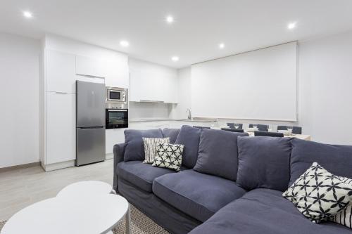 uma sala de estar com um sofá azul e uma cozinha em APARTAMENTO LUMINOSO EN CANGAS em Cangas