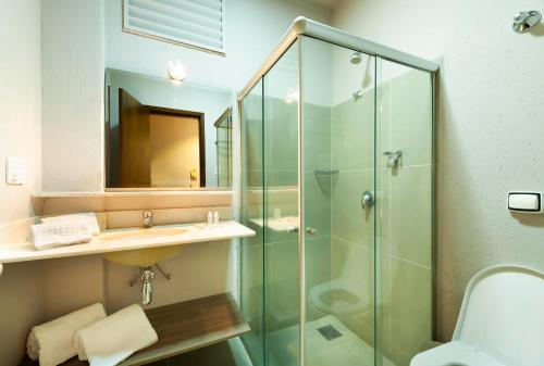 a bathroom with a glass shower and a sink at B&B HOTEL Uberlândia in Uberlândia