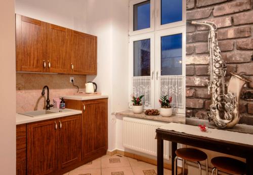 kuchnia z drewnianymi szafkami i saksofonem obok okna w obiekcie Nasze Kamienice Apartament Muzyczny z antresolą w mieście Rzeszów