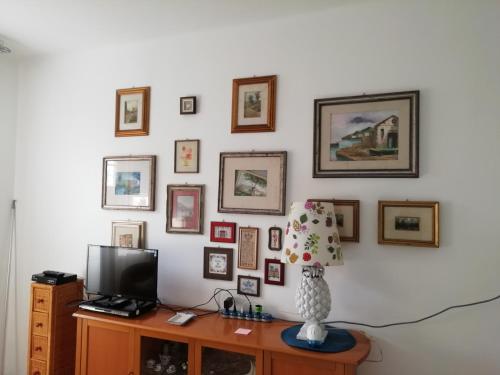 a room with a tv and a wall with pictures at SanBart Villetta con Giardino in San Bartolomeo al Mare