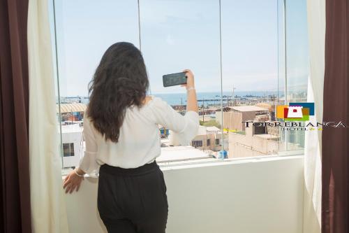 a woman taking a picture of a city from a window at Torreblanca Hotel in Ilo
