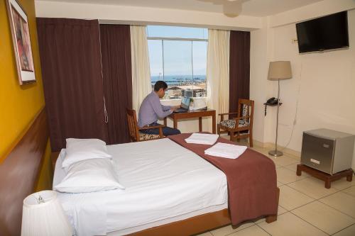 a man sitting at a desk in a hotel room at Torreblanca Hotel in Ilo