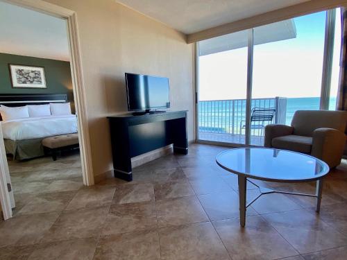 a hotel room with a bed and a tv and a table at Radisson Suite Hotel Oceanfront in Melbourne