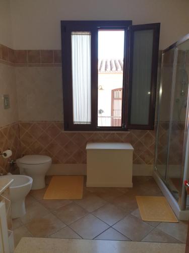 a bathroom with a toilet and a window at La Casa di Sara in Pula