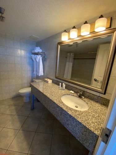 a bathroom with a sink and a mirror and a toilet at Radisson Suite Hotel Oceanfront in Melbourne
