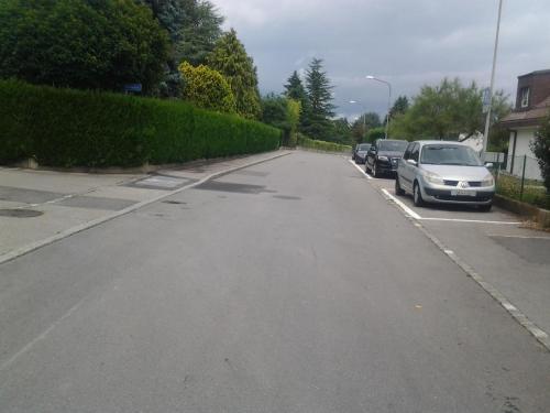 an empty street with cars parked on the side at Le Yanis in Lausanne