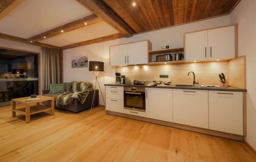 a kitchen with white cabinets and a living room at NATURPARKGUT - alpdeluxe Apartments in Holzgau