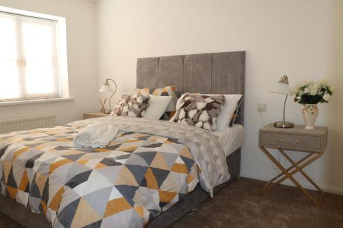 um quarto com uma cama com um edredão cinza e laranja em Cosy & Lovely Guesthouse with Free Parking & Close to Station em Slades Green