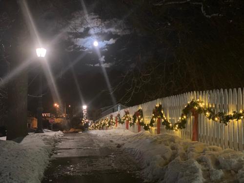 a fence covered in snow at night with christmas lights at Chambery Inn in Lee
