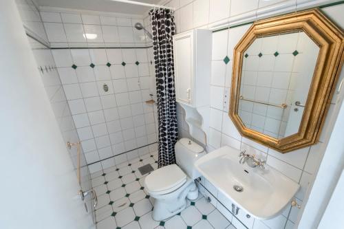 bagno con servizi igienici, lavandino e specchio di Grand Hotel Hønefoss a Hønefoss