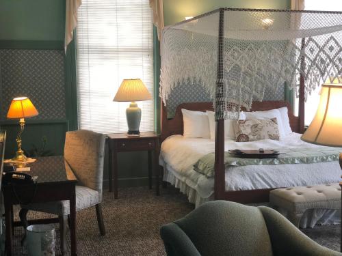 a bedroom with a canopy bed and a chair at Chambery Inn in Lee