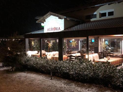 a restaurant with couches and tables in the night at Aurora Panzió in Bük