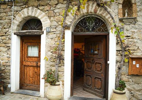 two doors in a stone building with flowers in front at Il Cappellaio Matto in Montalto Ligure