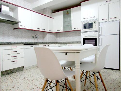 una cocina con armarios blancos y una mesa y sillas blancas. en www Parques de la Catedral travel com Parking privado Gratis, en León