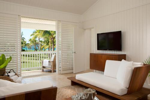 a living room with a white couch and a television at The Cove Eleuthera in Gregory Town