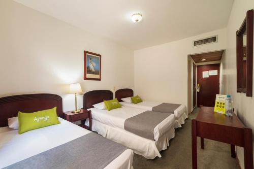a hotel room with three beds with green pillows at Ayenda 1408 Jaba Santiago de Cali in Cali
