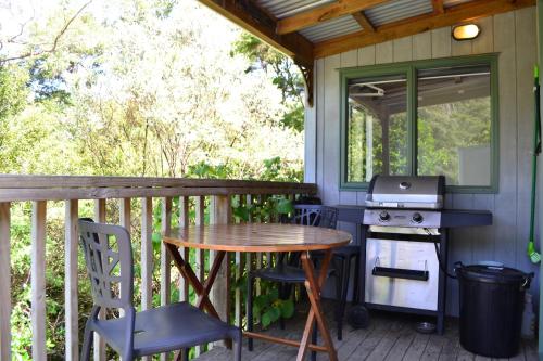 a screened porch with a table and a grill at Te Mata Lodge in Tapu