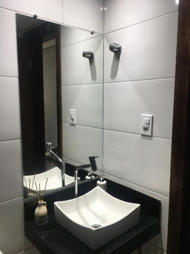 a bathroom with a sink and a mirror at Apartamento na Praia - Ilhéus in Ilhéus