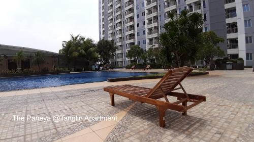 a wooden chair sitting next to a swimming pool at The Paneya @Tanglin Apartment in Surabaya