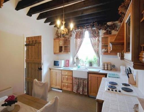 a large kitchen with a table and a window at Inglenook Cottage in Grange Over Sands