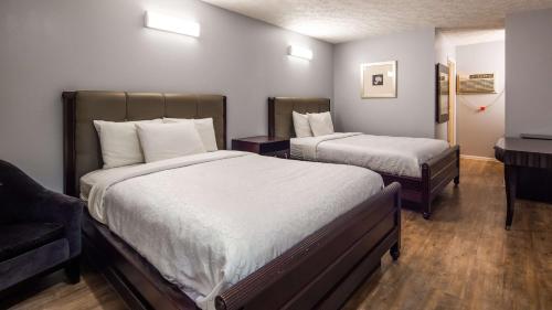 a hotel room with two beds and a chair at Apple Valley Inn Pigeon Forge in Pigeon Forge