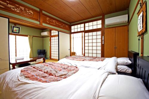 2 camas en una habitación con ventanas en Shirasakiso, en Yura